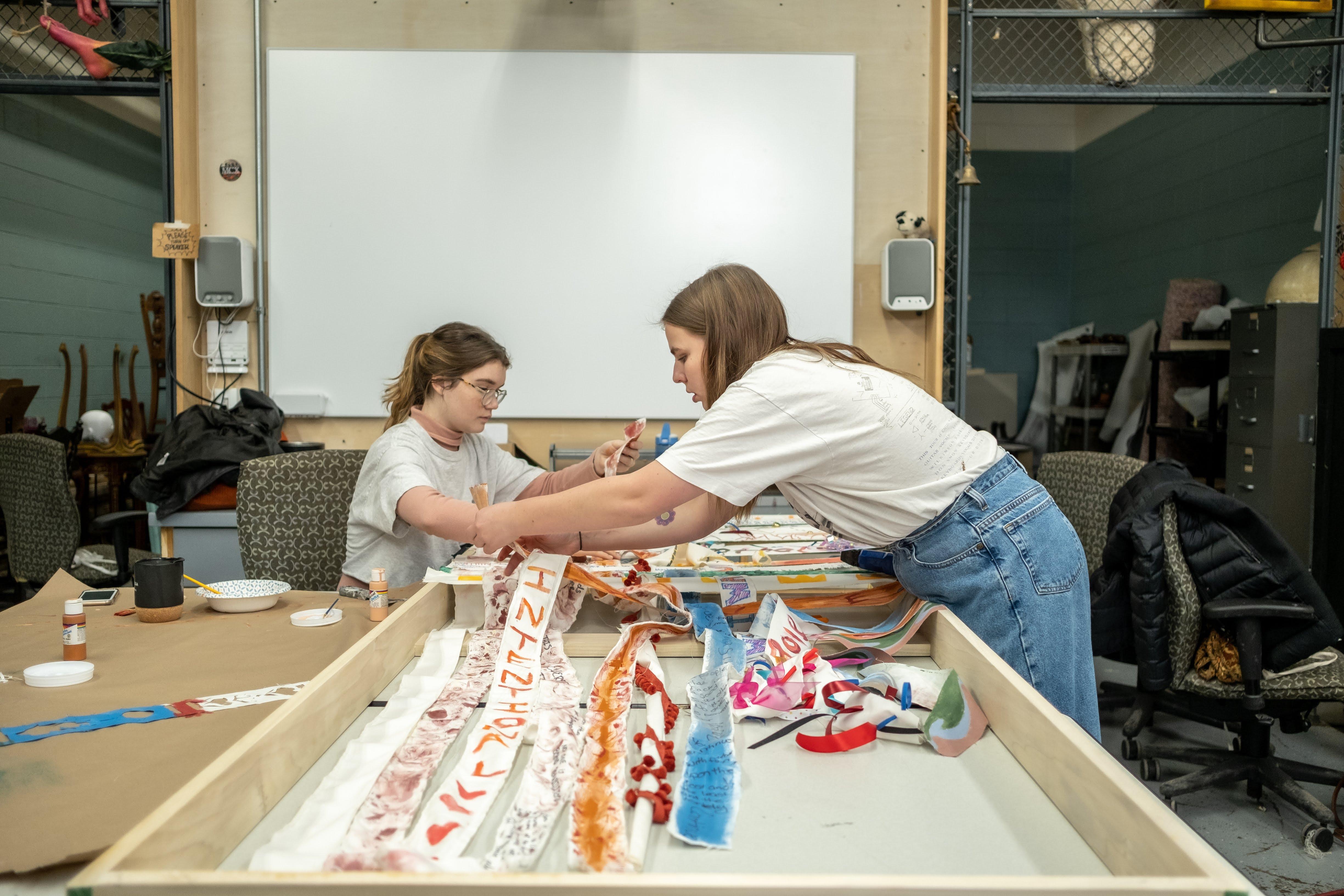 Jennings Leonard and Kate Baxter attach strips of cloth to a wooden frame. / Photo: Raunak Kapoor