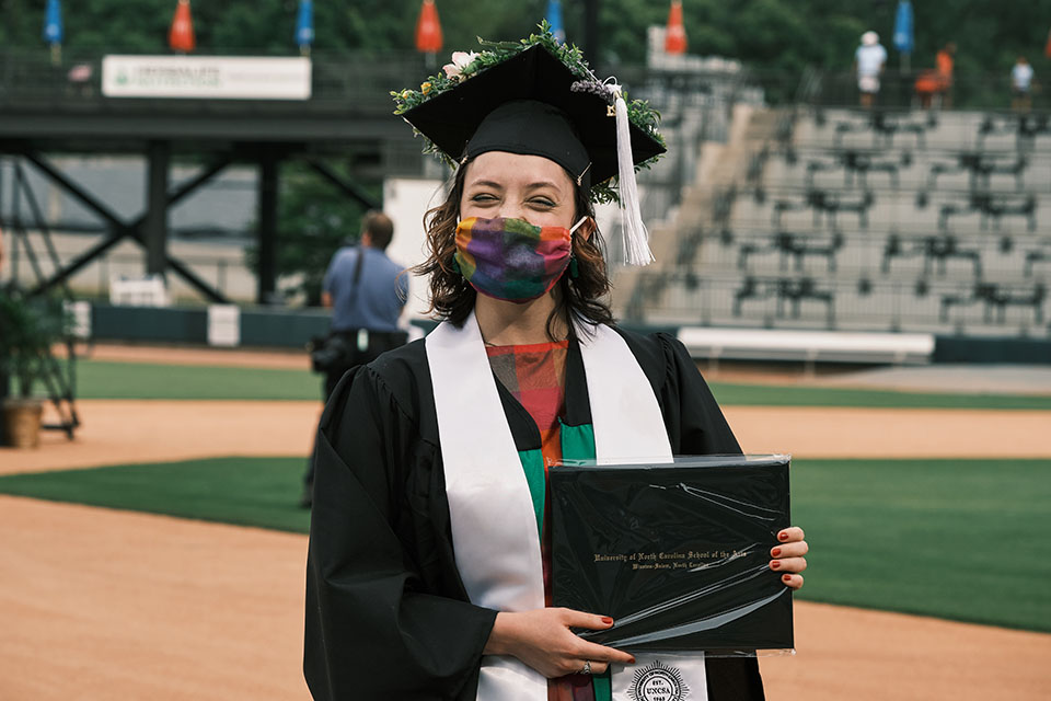 A University graduate poses with a newly-awarded diploma. / Photo: Wayne Reich