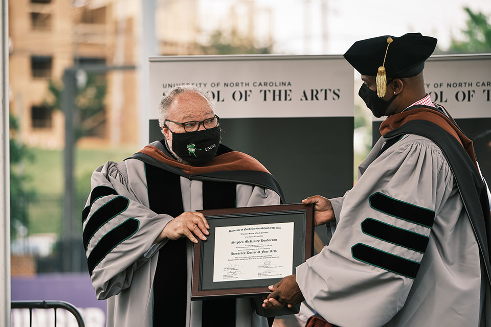 Drama alumnus Stephen McKinley Henderson is presented with an honorary doctorate by Provost Patrick Sims at the University Commencement ceremony. / Photo: Wayne Reich
