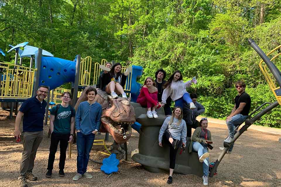 Division of Liberal Arts faculty Joe Mills and Mike Wakeford offer an elective course designed to break the typical student routine by taking weekly walks to points of interest and inspiration. Here they are with their students at the Dinosaur Park in Washington Park near campus. / Photo: Joe Mills 