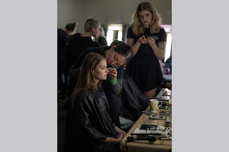 Amelia Brown applies makeup for a performer in Spring Awakening.
