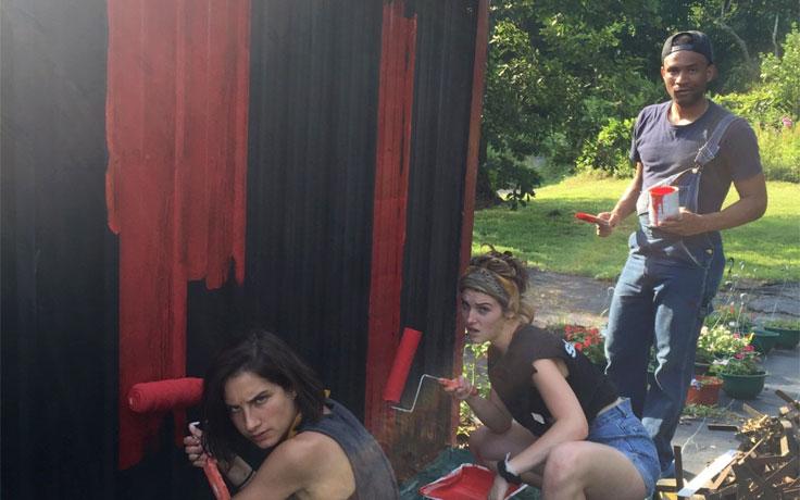 Hannah Myers (center) and UNCSA alumnus Lorenzo Roberts painting the farm stand.