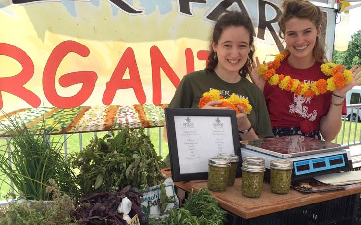 Hannah Myers (right) helps sell produce from Ryder Farm at the local farmer's market.