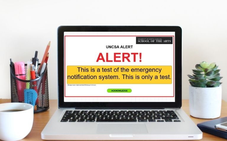 A laptop with a test UNCSA alert on the screen