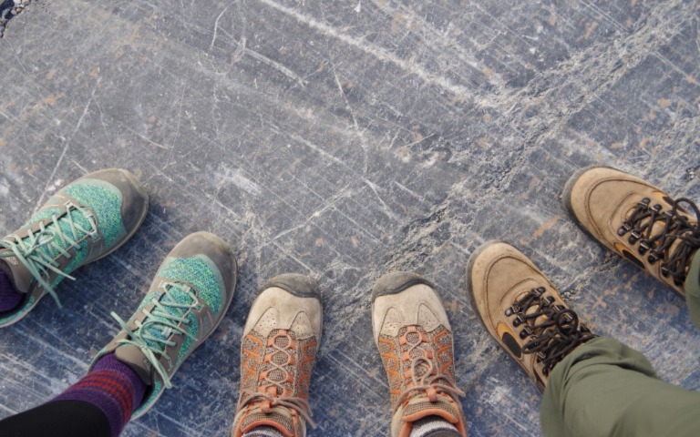 Three people standing together in hiking shoes