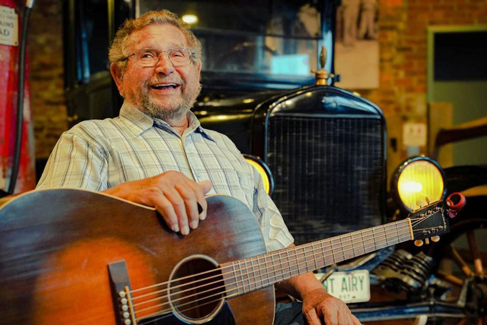 Chester McMillian smiling with his guitar