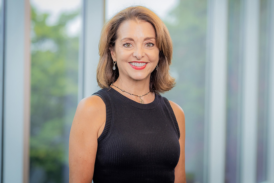 Lisa Mayer smiles and poses in front of windows