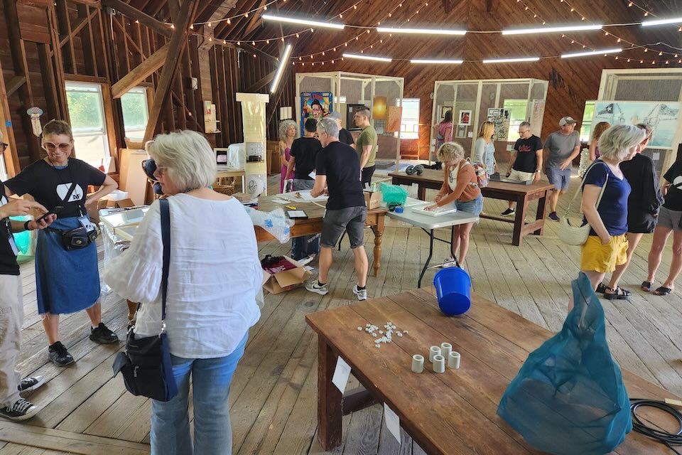 A diverse group of people in a room preparing artworks to be put on display.