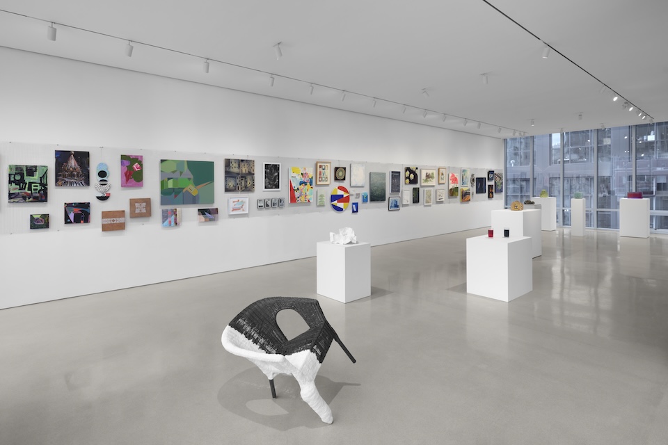 A gallery with many artworks displayed on the walls and on pedestals.