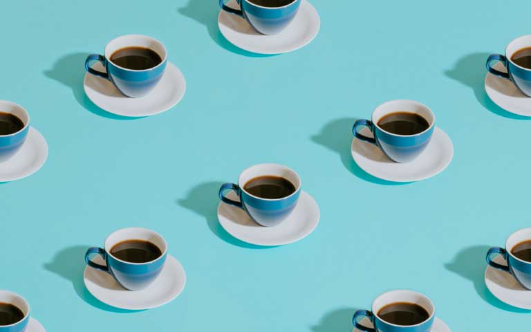 Repeated patter of filled coffee cups on blue background