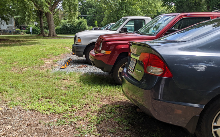 Cars parked incorrectly on the grass in gravel lot