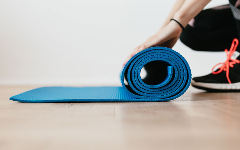 Person rolling out a blue yoga mat
