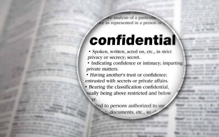 The word confidential magnified in a dictionary
