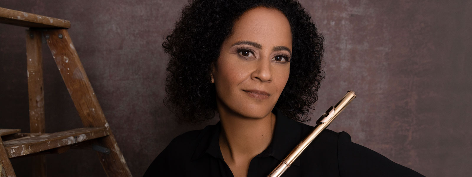 Black woman in a black shirt holding a flute