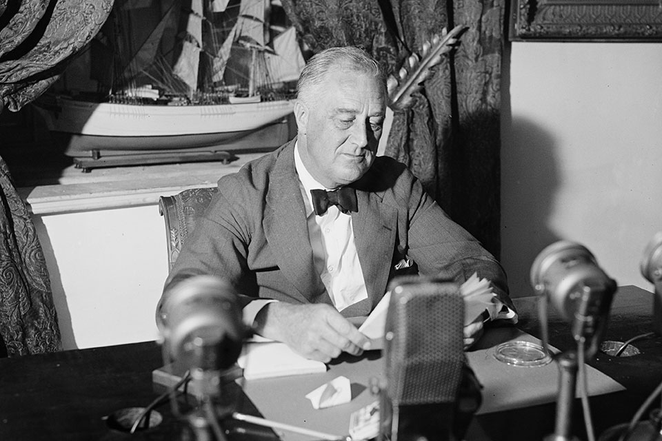 Franklin D. Roosevelt at a desk recording a radio broadcast