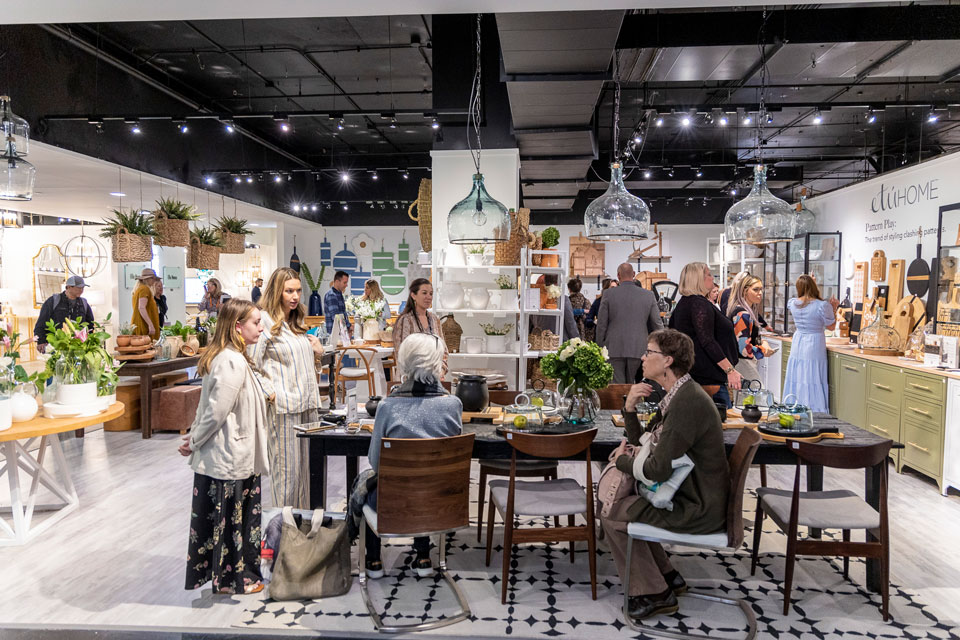  A group of people gathered around a table in a showroom, engaged in discussion and examining products.
