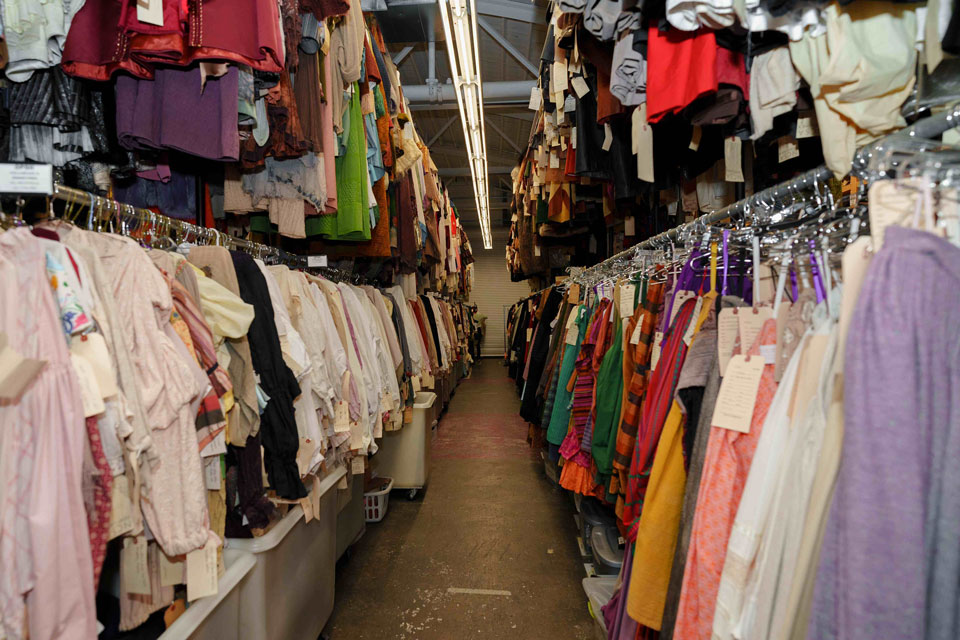 A spacious room filled with numerous clothing racks displaying a variety of garments.