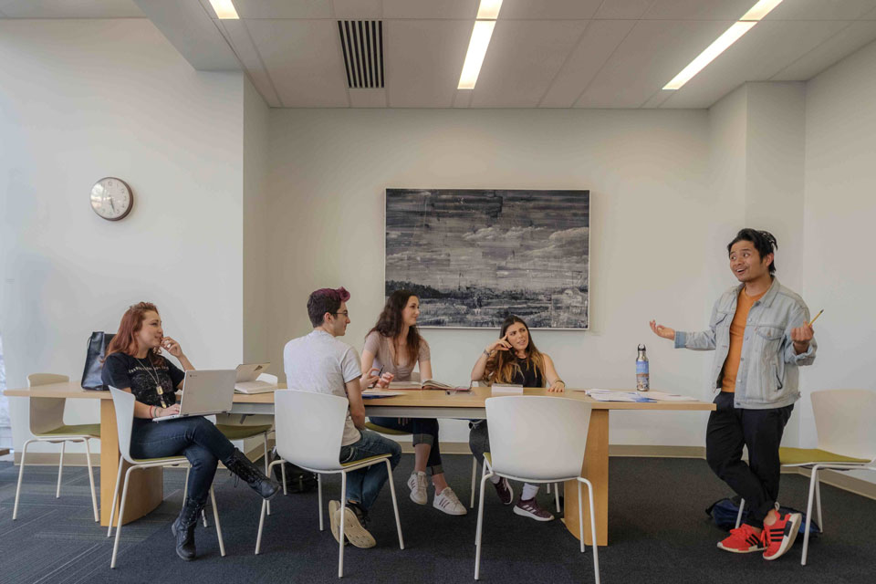 A group of diverse individuals engaged in discussion around a conference table in a modern office setting.