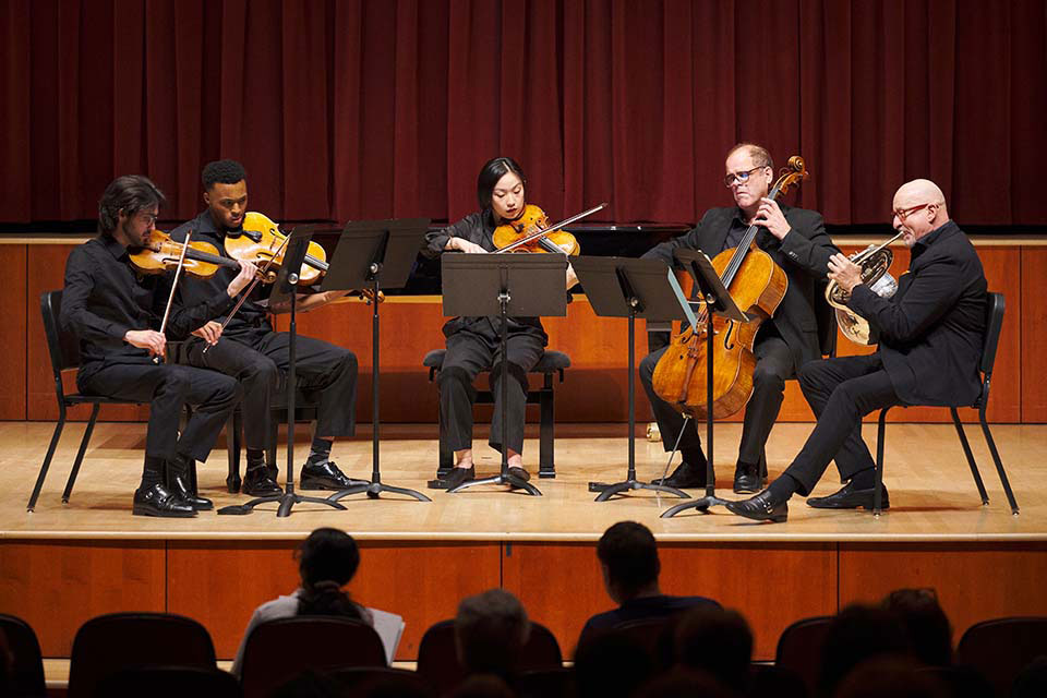 A group of musicians performing with violins and a cello during a concert, showcasing their musical talent and collaboration.