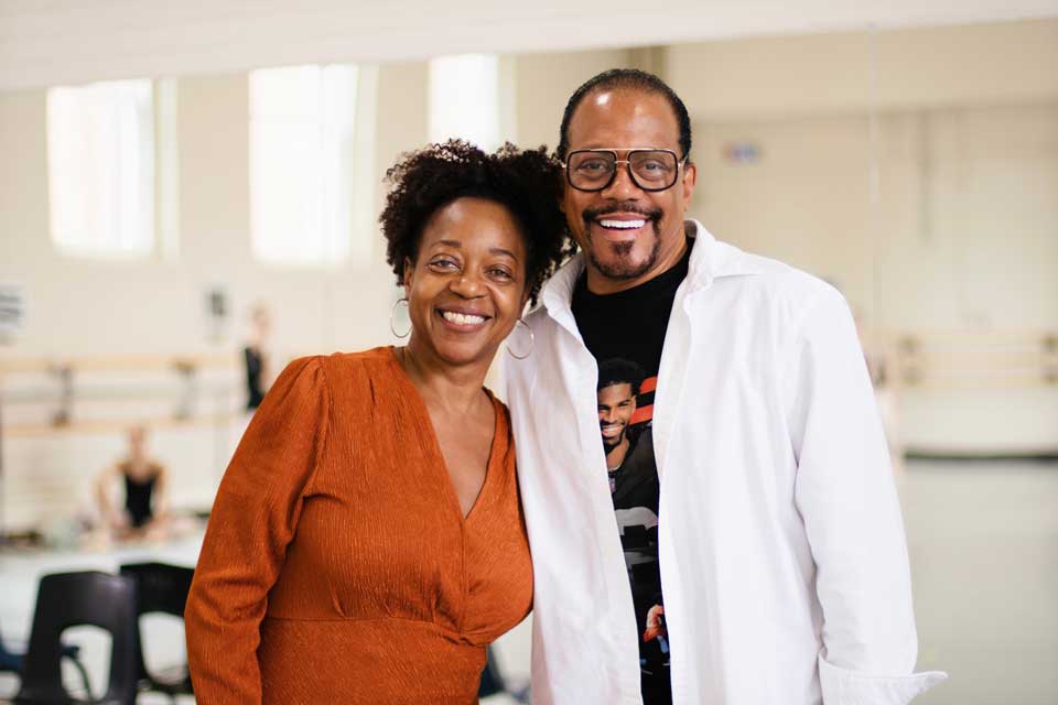 A man and woman stand together in a dance studio.