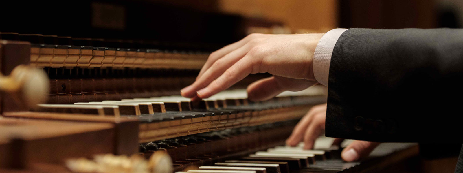 A suited individual is performing on an organ