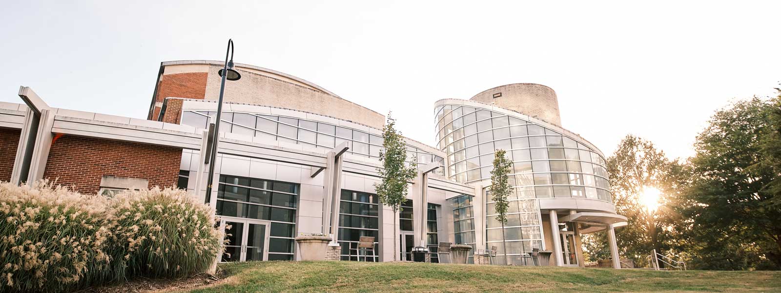 A building with tall glass windows and a grassy lawn.