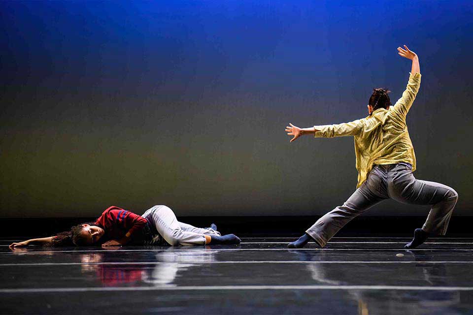 Two dancers performing gracefully on stage, showcasing their skills in a captivating dance performance.