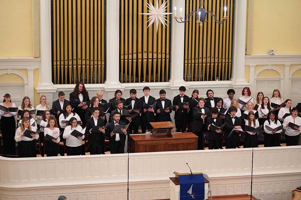 A choir performing under the direction of a choir leader, with members engaged in singing together