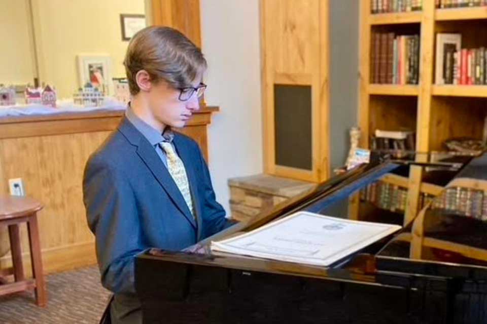 A student sits at a piano.