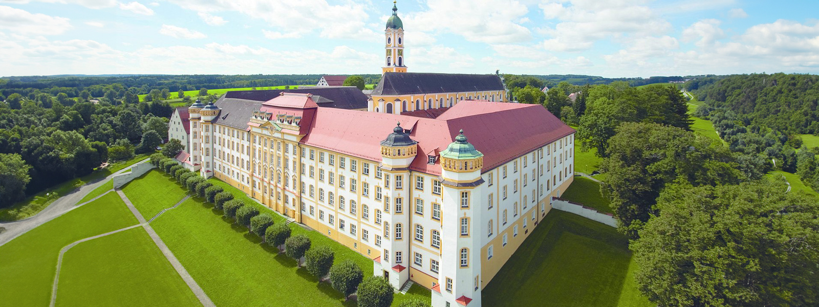 A castle stands majestically, surrounded by vibrant green grass under a clear blue sky.