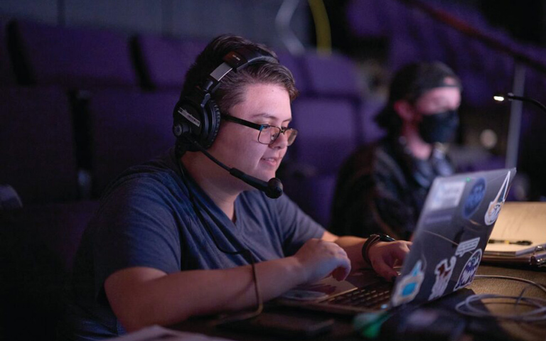 A person with headphones on smiling at a panel