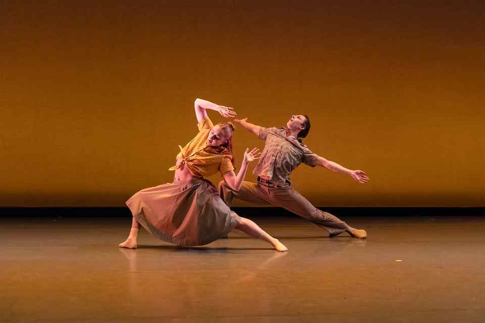 Two people are dancing and holding a strong pose with their arms held above their heads.