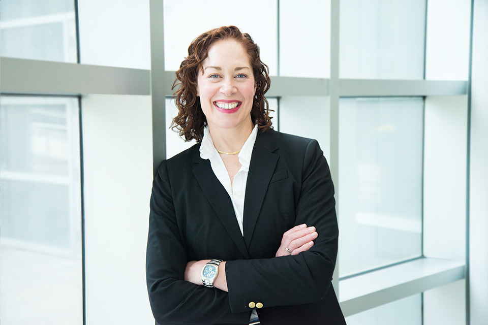 A woman smiling and standing with her arms crossed.