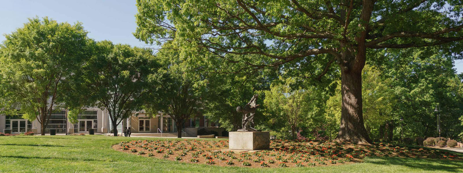 A statue with a bird perched stands in front of a historic building.